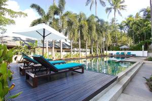 una terraza con sillas y una sombrilla junto a la piscina en 1Gbps Internet Apartment The Park Choeng Mon, en Koh Samui 