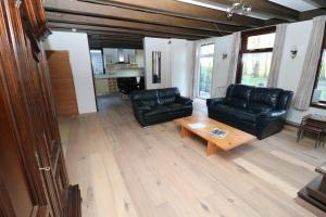 a living room with black leather couches and a coffee table at Hof Zuidvliet in Wolphaartsdijk