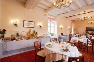 ein Esszimmer mit Tischen und Stühlen sowie eine Küche in der Unterkunft La Villa des Longchamps Location du samedi au samedi in Saint-Jouan-des-Guérets