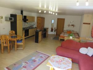 a living room with a red couch and a kitchen at Ferienwohnungen Haus Albert in Großheubach