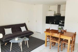 a living room with a black couch and a table at Appartement plage de Trestraou in Perros-Guirec