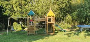 a wooden playset in a yard with a playground at Cosy Er Lann Gîte Séquoïa in Val Couesnon