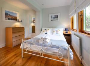 Schlafzimmer mit einem weißen Bett und Holzboden in der Unterkunft Glentruim Homestay B&B in Newtonmore