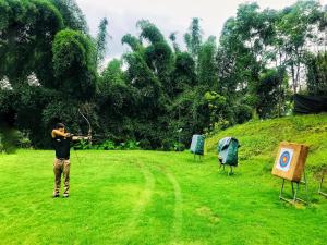 a man aiming a bow and arrow in a field at Banyan Tree Yangshuo in Yangshuo