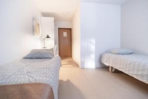 two beds in a room with white walls at Motelli Marjaana in Kaustinen