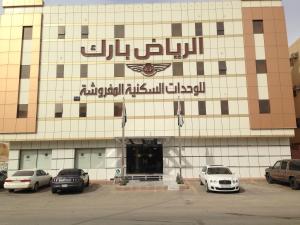 a building with cars parked in a parking lot at الرياض بارك للاجنحة الفندقية in Riyadh