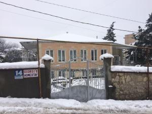 a gate in front of a house covered in snow at Giorgi's Homestay in Kutaisi