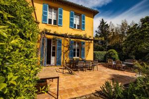 a yellow house with a patio with tables and chairs at Villa Les Glycines in Saint-Tropez