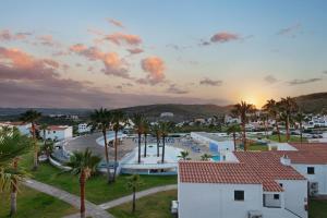 a view of a town with palm trees and the sunset at TRH Tirant Playa in Fornells