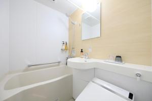 La salle de bains est pourvue d'une baignoire blanche, d'un lavabo et d'un miroir. dans l'établissement Hotel NewNagano NeXT, à Nagano