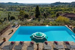 una piscina con sombrilla y sillas en Villa Senaia, en Castiglion Fiorentino