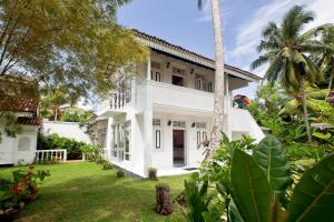an exterior view of a white house with a yard at Chitra Ayurveda in Bentota