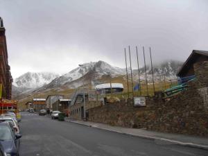 a street with a mountain in the background with cars parked at Apartamentos Frontera Blanca Nievesol in Pas de la Casa