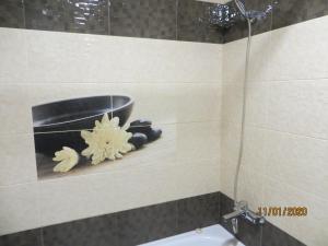 un bagno con una ciotola nera e fiori su un muro di Замечательная квартира с современным ремонтом рядом с метpо Холодная гора a Charkiv Altre 6 foto