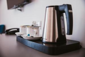 eine Kaffeemaschine auf einem Regal mit Tassen darauf in der Unterkunft HOTEL Art Cafe in Nakło nad Notecią