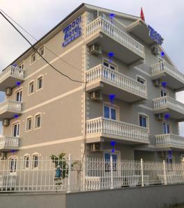 a large building with balconies and a white fence at Doci Seven Hotel in Velipojë