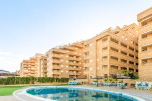 an apartment with a swimming pool in front of a building at Vacaciones Oromarina Azahar in Oropesa del Mar