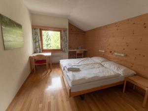 a bedroom with a bed and a wooden wall at Silserhof - ankommen, auftanken, aufatmen in Sils Maria