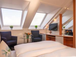 a bedroom with a bed and two chairs and a tv at Haus Nickels in Helgoland