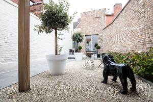 una estatua de perro negro sentada en un patio de grava en Maison de la Paix en Poperinge