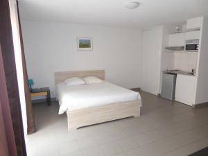 a white bedroom with a bed and a kitchen at Résid'Artel Cadarache - ITER in Saint-Paul-lez-Durance