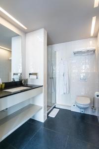 a white bathroom with a toilet and a sink at Hotel de la Paix in Poperinge