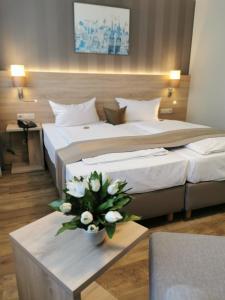 a hotel room with two beds with flowers on a table at Hotel Cristal in Nuremberg