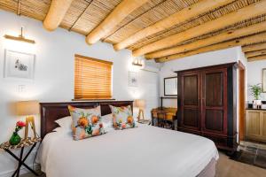 a bedroom with a white bed and a wooden cabinet at Roosenwijn Guesthouse in Stellenbosch