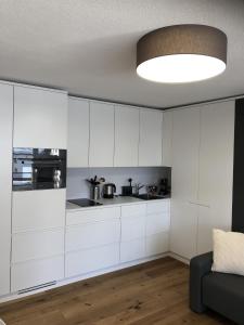 eine Küche mit weißen Schränken und einer großen Leuchte in der Unterkunft Ferienwohnung 405 Haus Allod in Lenzerheide