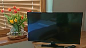 a computer monitor sitting on a desk next to a vase of flowers at Apartment Prossegger in Neukirchen am Großvenediger