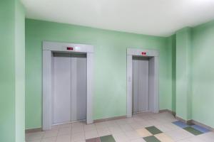 two elevators in an empty room with green walls at Однокомнатная квартира в новостройке недалеко от Аэропорта, ЖД Вокзала in Tyumen