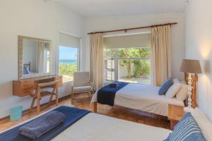 1 dormitorio con 2 camas, escritorio y ventana en Anna's On The Beach, en Cape St. Francis