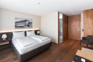 
a bedroom with a bed, a chair, and a desk at Hotel one66 (free parking garage) in St. Gallen
