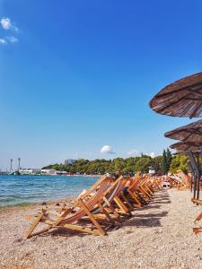 a row of beach chairs and umbrellas on a beach at Apartments Beleca in Biograd na Moru