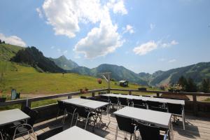 a patio with tables and chairs with mountains in the background at APPARTEMENT PIED DES PISTES - SAINT JEAN D'AULPS STATION - 4 Personnes - RELAIS S36 in Saint-Jean-d'Aulps