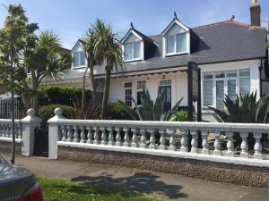 a white fence in front of a house with palm trees at Trewinda Lodge in Newquay