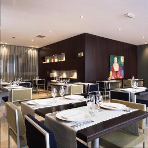 a restaurant with tables and chairs and a painting on the wall at Hotel Ciutat Martorell in Martorell