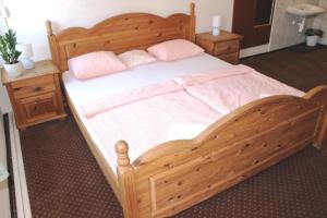 a bedroom with a wooden bed with pink pillows at Penzion Varšavjanka in Harrachov