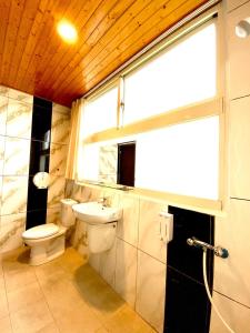 Un baño con inodoro, lavabo y ventana. en Mini Home B&B, en Kangle