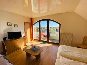 a living room with a couch and a tv and a table at Pension Schmitt in Waldfenster