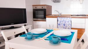 TresnuraghesにあるWelcomely - La Nassa - dimora vista mareのキッチン(白いテーブル、食器、テレビ付)