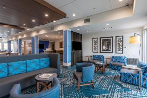 a hotel lobby with blue chairs and a couch at Holiday Inn Express & Suites Gainesville - Lake Lanier Area, an IHG Hotel in Gainesville