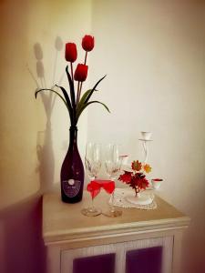 Anamonì Bed and Relax في بينيفنتو: طاولة مع مزهرية مع الورود الحمراء وكؤوس النبيذ
