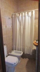 uma casa de banho com um WC e uma cortina de chuveiro em La Roca de la Patagonia em Villa La Angostura