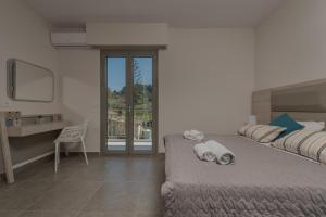 a bedroom with a bed and a desk and a window at Casa 77 Zante by Karras Hotels in Zakynthos Town