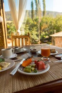 uma mesa com um prato de comida e um copo de sumo de laranja em Pousada Papyrus em Tiradentes