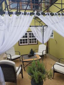 a patio with white curtains and a table and chairs at Pousada Papyrus in Tiradentes