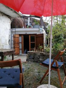 a red umbrella and a chair and a table at Isminis Petroktisto Holidays Stonehouse in Palechori