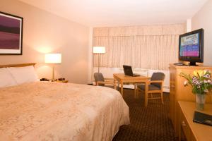 a hotel room with a bed and a desk with a laptop at Woodlands Inn & Suites in Fort Nelson