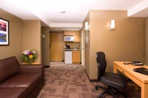 an office with a couch and a desk and a kitchen at Woodlands Inn & Suites in Fort Nelson
